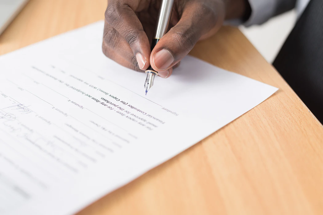 A picture of a person signing an agreement