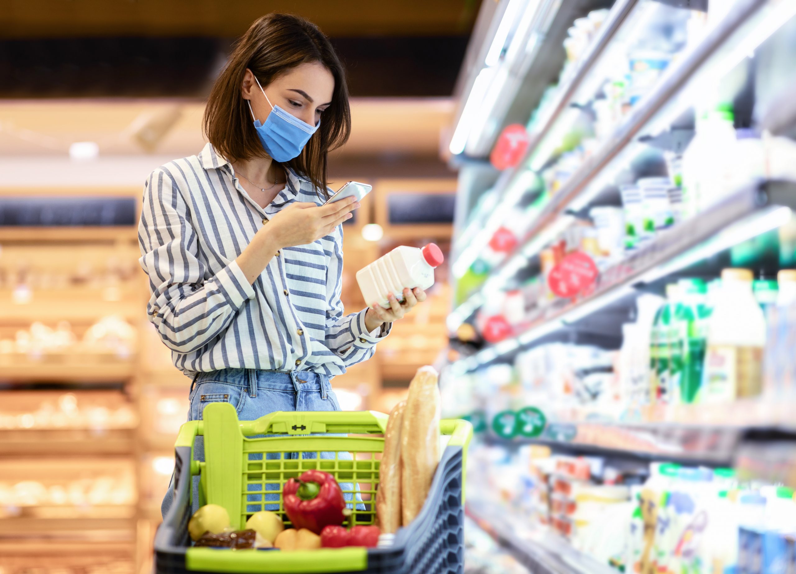 A woman taking a picture of a bottled milk in a grocery store